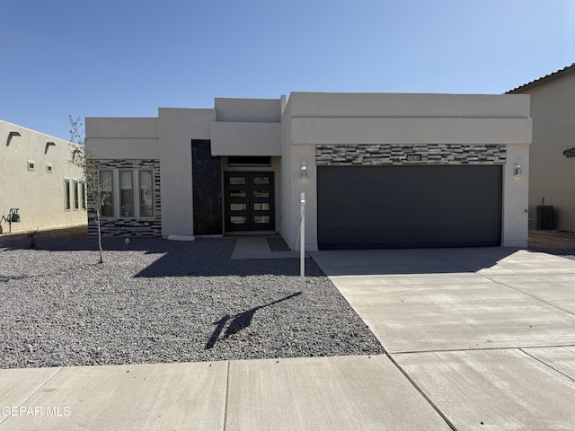 view of front facade with driveway, an attached garage, central AC, stucco siding, and stone siding