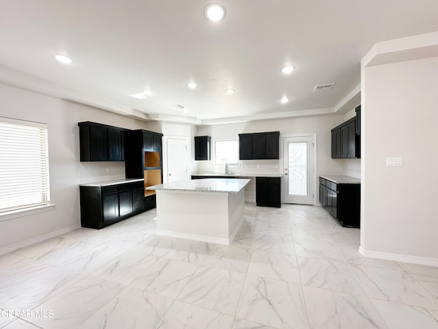 kitchen featuring recessed lighting, a center island, baseboards, and dark cabinets