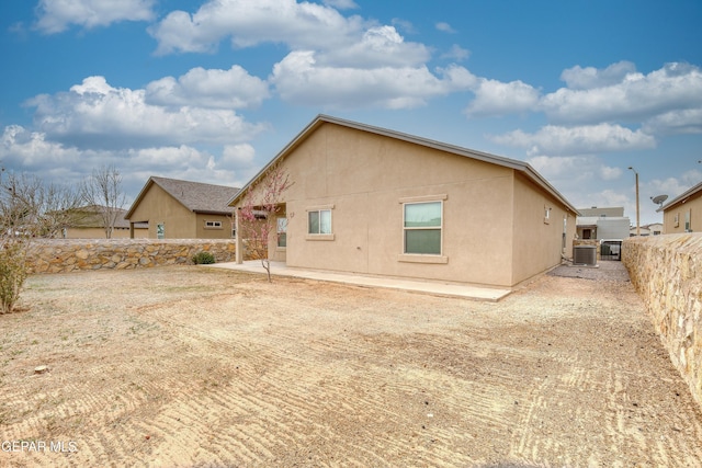 rear view of house featuring stucco siding, a patio, central AC unit, and a fenced backyard