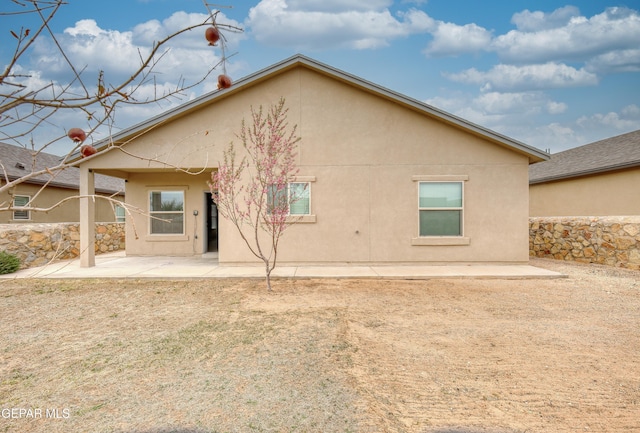 rear view of house featuring a patio area and stucco siding