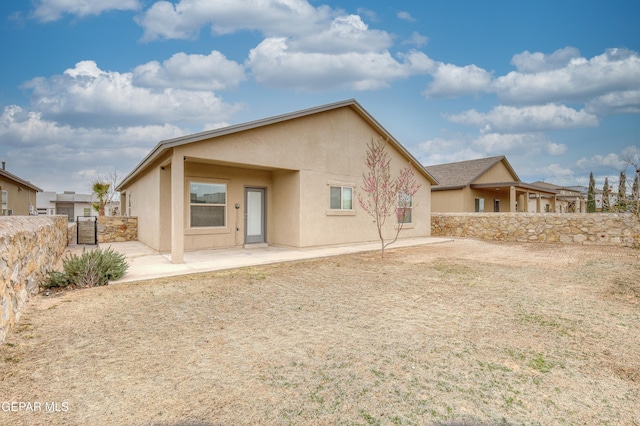 rear view of property with stucco siding, a patio, and fence