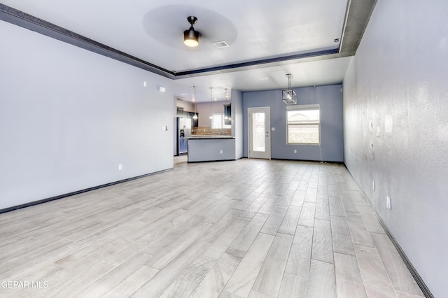 unfurnished living room featuring a ceiling fan, baseboards, visible vents, wood tiled floor, and a tray ceiling