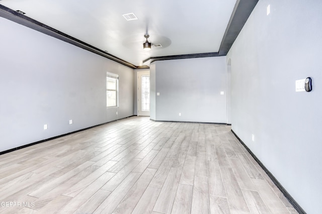 empty room featuring visible vents, light wood-type flooring, and baseboards