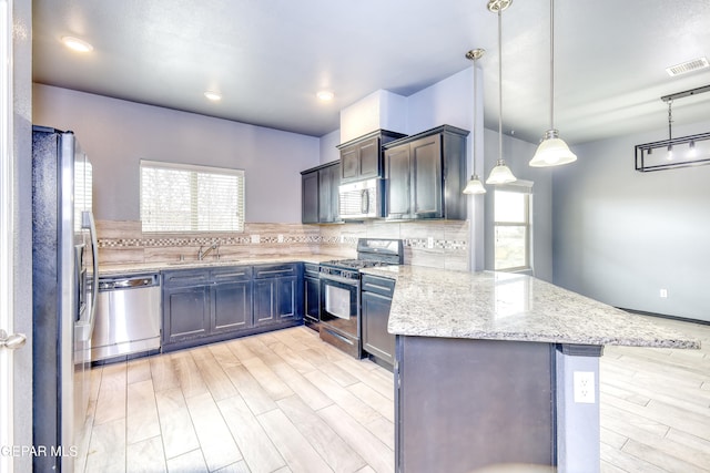 kitchen featuring visible vents, plenty of natural light, backsplash, stainless steel appliances, and a peninsula