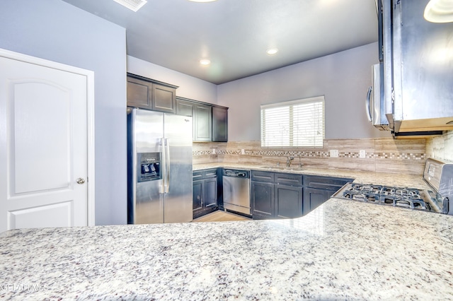 kitchen featuring light stone countertops, recessed lighting, a sink, decorative backsplash, and appliances with stainless steel finishes