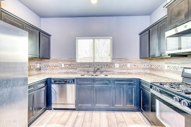 kitchen featuring a sink, light stone countertops, backsplash, and appliances with stainless steel finishes