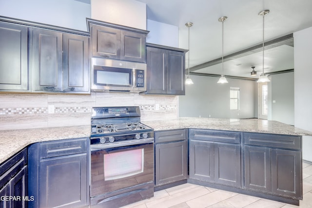 kitchen featuring stainless steel microwave, range with gas stovetop, a peninsula, decorative backsplash, and light stone countertops