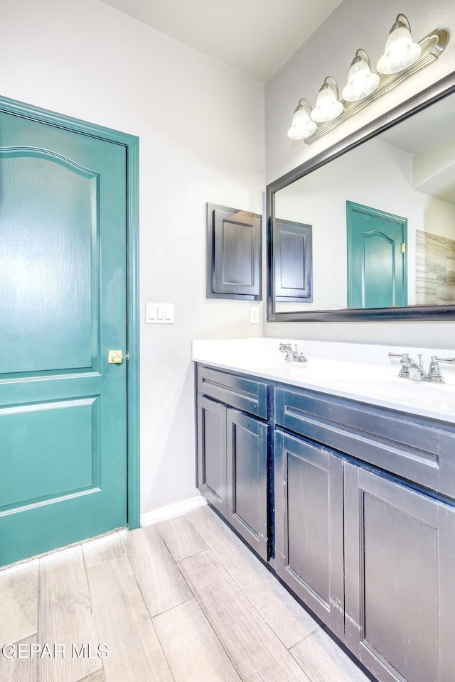 full bath featuring double vanity, baseboards, and a sink