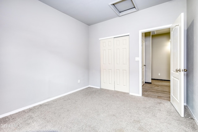 unfurnished bedroom with visible vents, a closet, carpet flooring, baseboards, and attic access