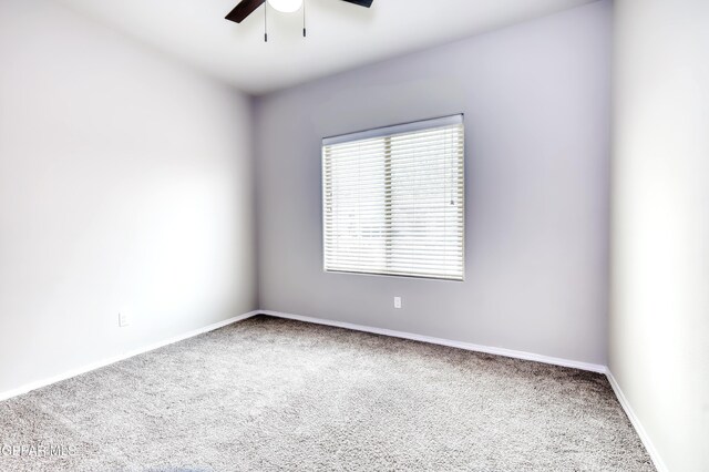 carpeted spare room featuring a ceiling fan and baseboards