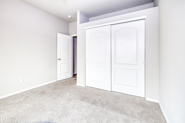 unfurnished bedroom with carpet, baseboards, and a closet