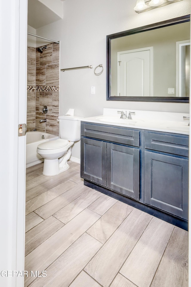 full bath with vanity, baseboards, wood tiled floor, bathtub / shower combination, and toilet