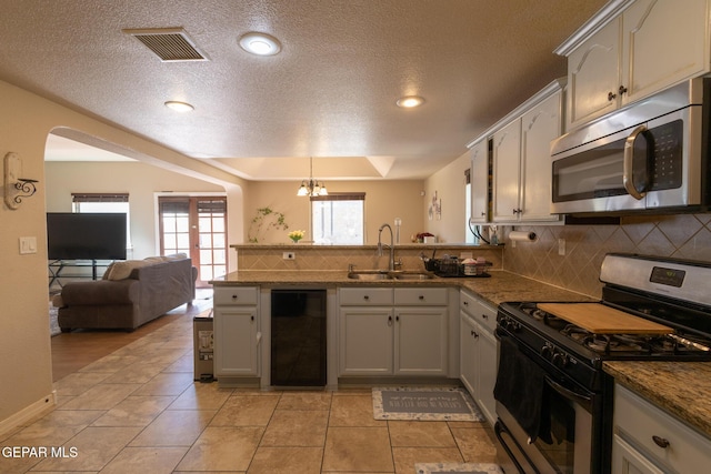 kitchen featuring beverage cooler, visible vents, a peninsula, a sink, and stainless steel appliances