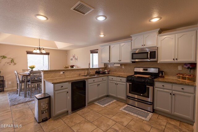 kitchen featuring visible vents, beverage cooler, a sink, stainless steel appliances, and an inviting chandelier