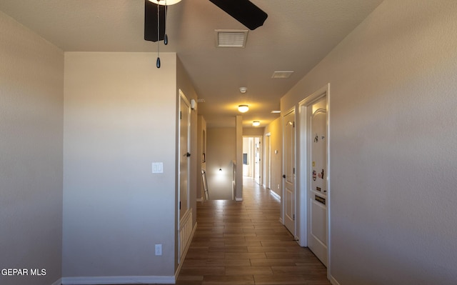 corridor featuring visible vents, baseboards, and wood finished floors