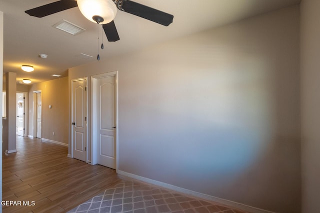 spare room with visible vents, baseboards, wood finished floors, and a ceiling fan