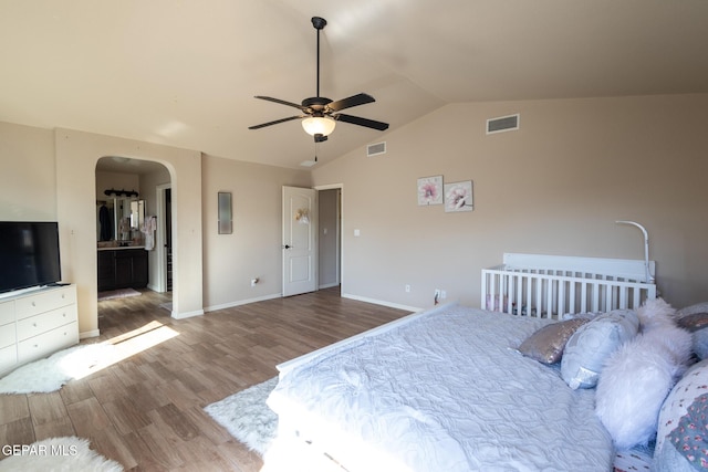 bedroom featuring arched walkways, visible vents, lofted ceiling, and wood finished floors