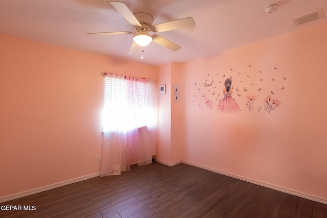 empty room with visible vents, baseboards, a ceiling fan, and dark wood-style flooring