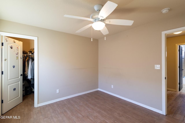 unfurnished bedroom featuring a spacious closet, a closet, baseboards, and wood finished floors