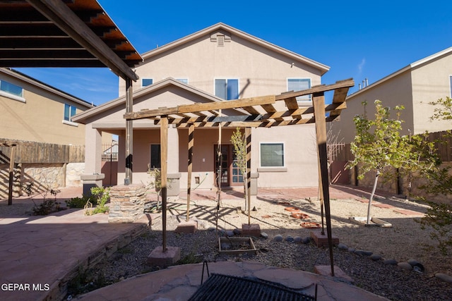 rear view of property featuring a pergola, a patio area, fence, and stucco siding