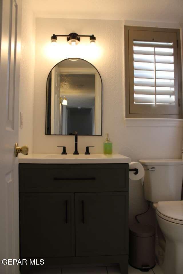 half bath featuring vanity and toilet