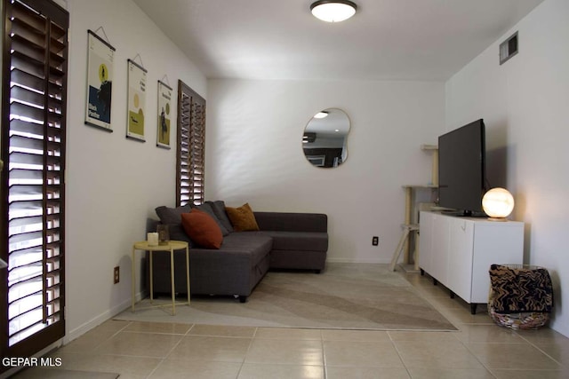 living area featuring light tile patterned floors, baseboards, and visible vents