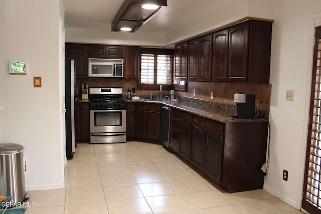 kitchen with baseboards, dark brown cabinetry, decorative backsplash, stainless steel appliances, and a sink