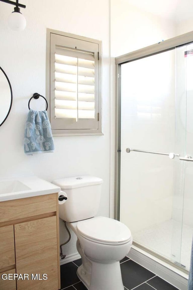 bathroom featuring tile patterned floors, a stall shower, toilet, and vanity