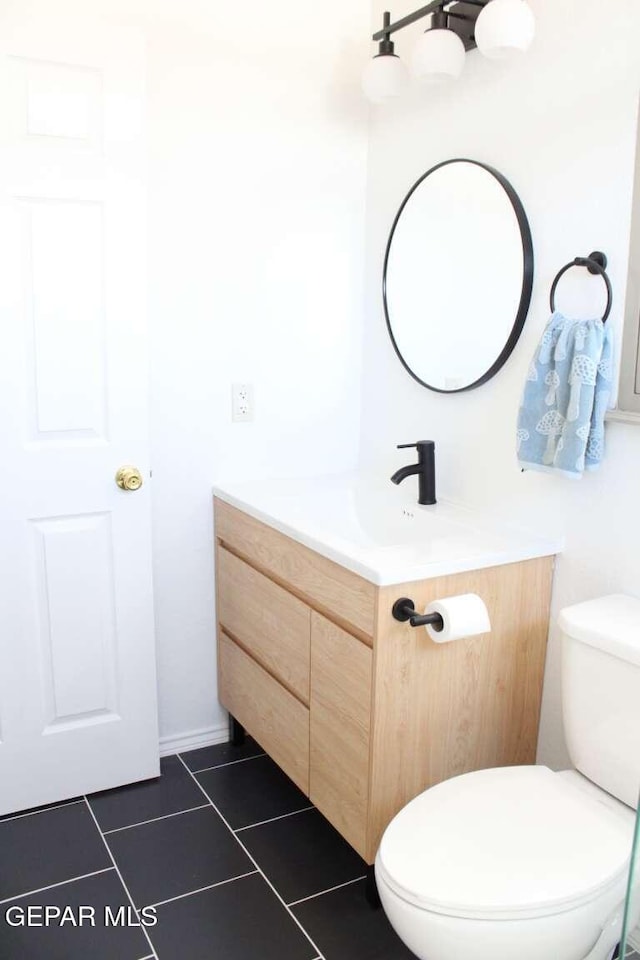 half bathroom featuring toilet, vanity, and tile patterned flooring