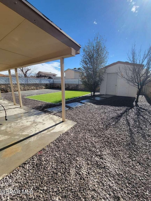 view of yard featuring an outbuilding, a storage unit, fence, and a patio