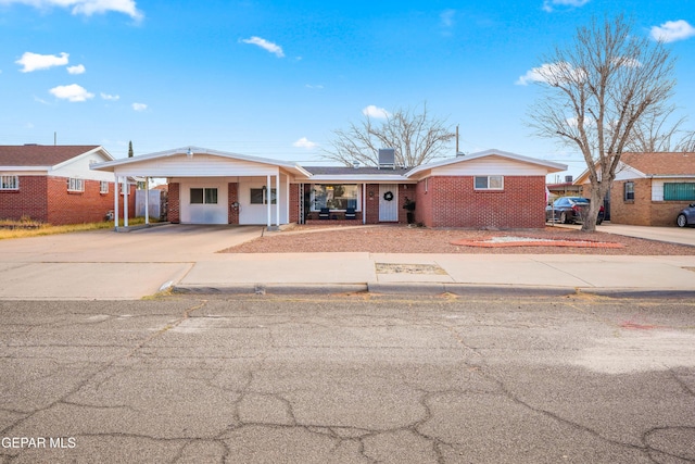 view of front of property featuring an attached carport, brick siding, and driveway