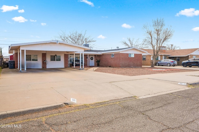 view of front of house with an attached carport, concrete driveway, and brick siding