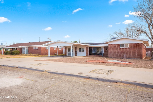 ranch-style house with driveway, a carport, and brick siding