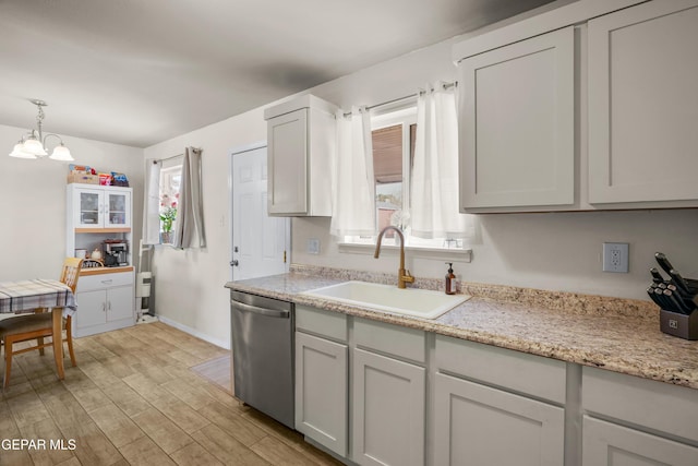 kitchen featuring a sink, decorative light fixtures, stainless steel dishwasher, light wood finished floors, and a chandelier