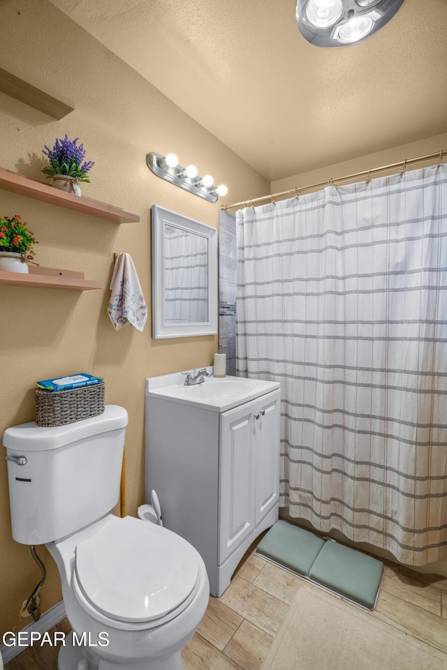 bathroom with vanity, toilet, a shower with curtain, and a textured ceiling