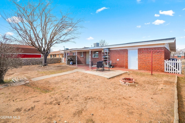 rear view of house with a patio area, fence, brick siding, and a fire pit