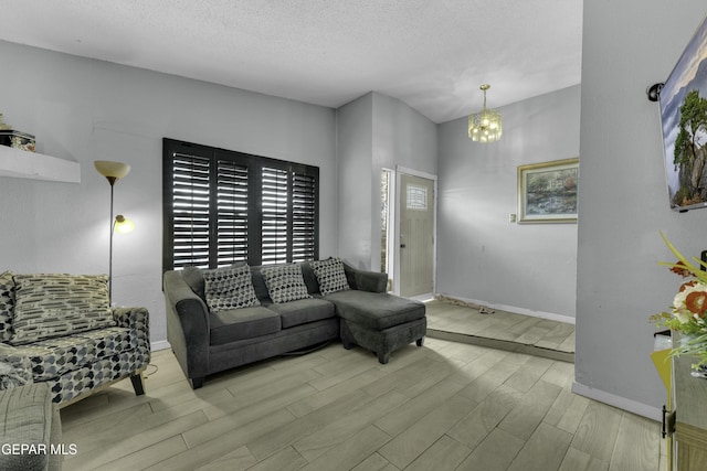 living area with an inviting chandelier, wood finished floors, baseboards, and a textured ceiling