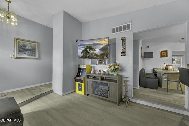 interior space featuring wood finish floors, visible vents, baseboards, and a notable chandelier