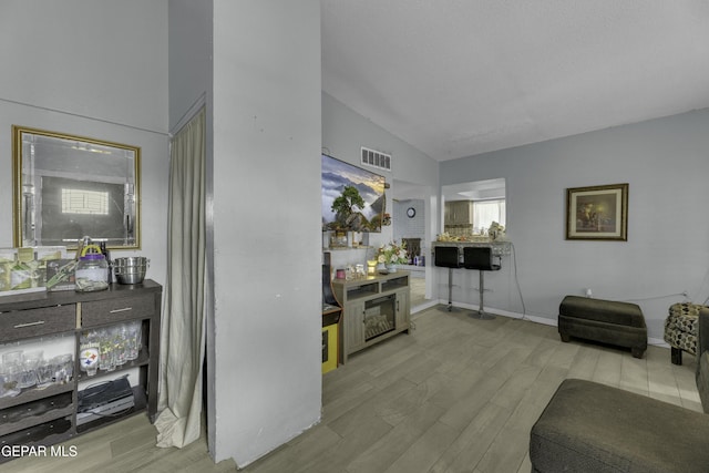 living room featuring visible vents, lofted ceiling, and wood finished floors