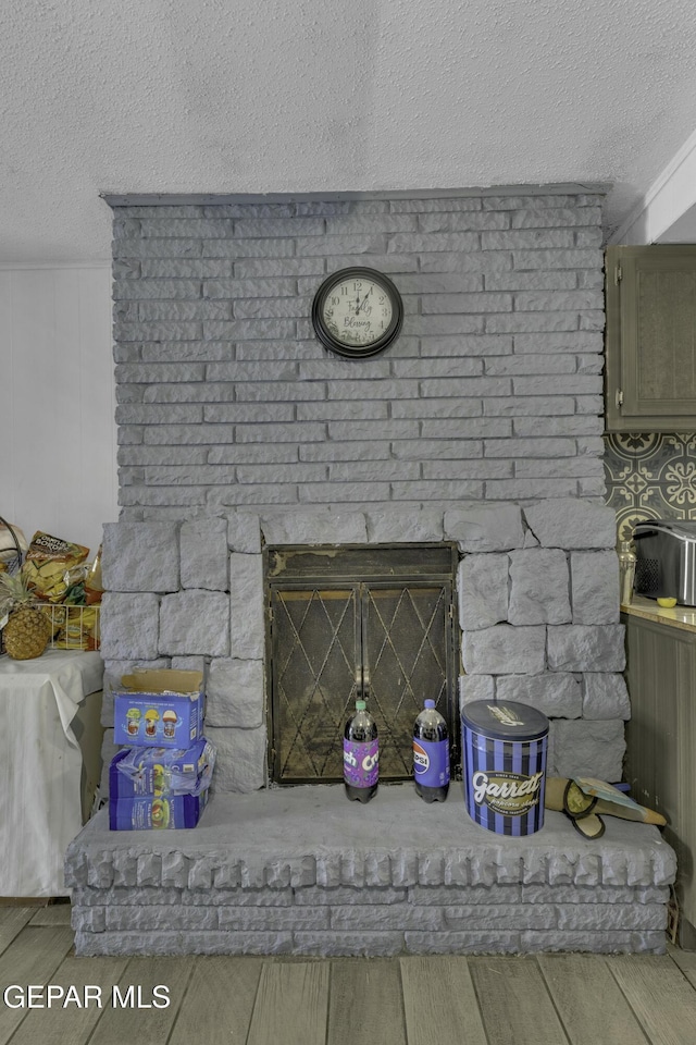 details featuring a brick fireplace, wood finished floors, and a textured ceiling