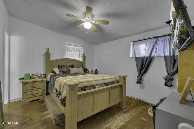 bedroom with dark wood finished floors, lofted ceiling, a ceiling fan, and a textured ceiling