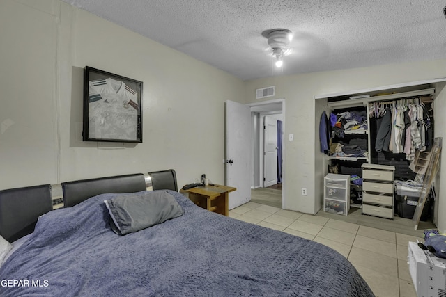 bedroom with light tile patterned floors, visible vents, a closet, and a textured ceiling