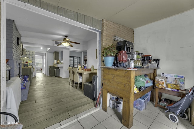 kitchen with wood finished floors, a ceiling fan, and brick wall