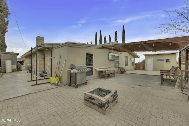 back of house featuring an outbuilding, a fire pit, and a patio area