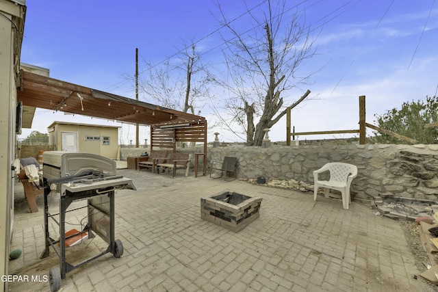 view of patio featuring an outbuilding, fence, a shed, an outdoor fire pit, and a grill