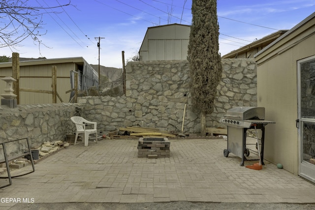 view of patio with area for grilling, a fire pit, and fence