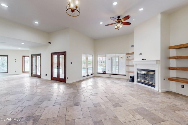 unfurnished living room with stone tile flooring, a glass covered fireplace, plenty of natural light, and a ceiling fan