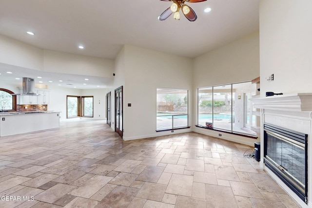 unfurnished living room featuring recessed lighting, a tile fireplace, a high ceiling, and ceiling fan