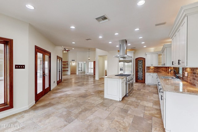 kitchen featuring visible vents, island exhaust hood, a sink, decorative backsplash, and french doors