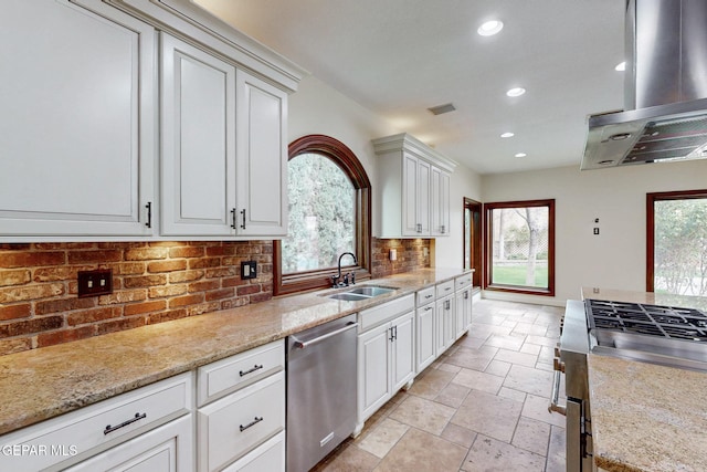 kitchen featuring island exhaust hood, a sink, tasteful backsplash, stone tile flooring, and stainless steel appliances